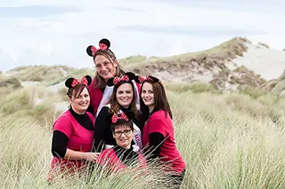 Groupe de femmes en tenues assorties avec des oreilles de Mickey dans les dunes