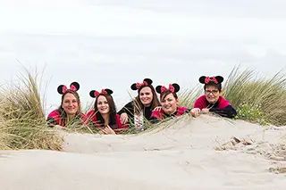 Femmes jouant à cache-cache dans les dunes, coiffées d'oreilles de Mickey
