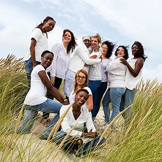 Groupe de femmes souriantes en tenues blanches sur une plage
