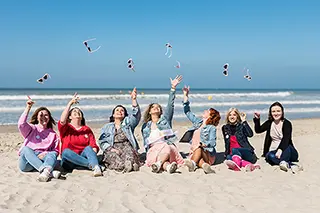 Amies assises sur le sable lançant des confettis en l'air
