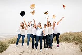 Femmes lançant des chapeaux en l'air sur la plage