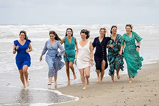 Femmes en robes colorées courant le long du rivage