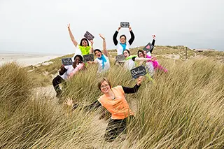 Groupe de femmes enjouées tenant des pancartes avec des messages joyeux dans les dunes