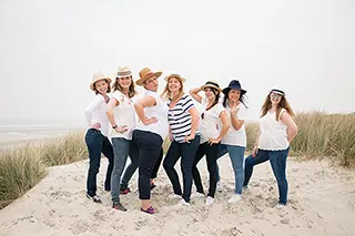 Groupe de femmes portant des chapeaux et posant avec confiance sur la plage