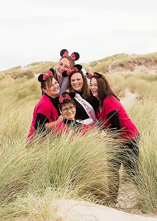 Groupe de femmes souriantes avec des oreilles de Mickey dans les dunes