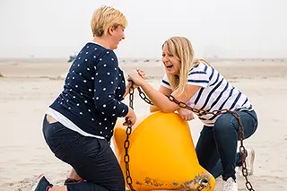 Deux femmes riant et partageant un moment joyeux sur une bouée à la plage