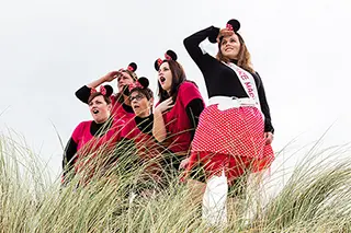 Groupe de femmes habillées en rouge et noir observant depuis les dunes