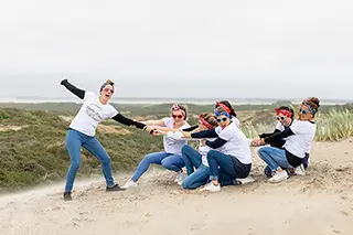 Groupe d'amis participant à un faux tir à la corde sur des dunes