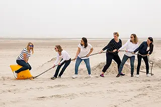 Femmes jouant au tir à la corde sur la plage, effort et amusement