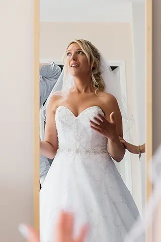 Mariée en robe de mariée émue devant le miroir