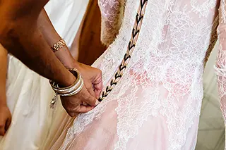 Mains ajustant le laçage d’une robe de mariée