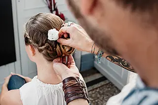 Enfant recevant une coiffure de mariage avec une fleur blanche