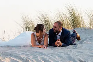 Mariés allongés sur une dune partageant un moment de complicité