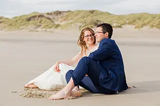 Mariés assis sur le sable de la plage partageant un moment de détente