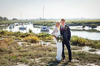Mariés posant devant un port maritime ensoleillé