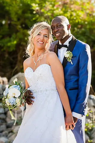 Couple marié posant souriant, marié en costume bleu et mariée en robe blanche
