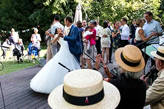 Mariés dansant pendant que les invités les entourent et applaudissent lors d'une réception de mariage en plein air.