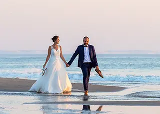 Mariés marchant main dans la main sur la plage