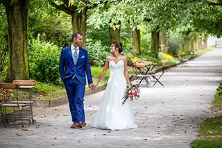 Mariés se tenant par la main sur un chemin bordé d'arbres