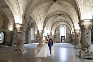 Mariés posant pour une photo dans la majestueuse architecture d'une abbaye ancienne.