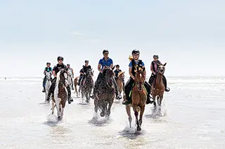 Groupe de cavaliers au galop sur la plage
