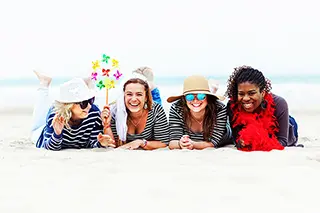 4 filles souriantes allongées sur le sable pour un shooting photo EVJF