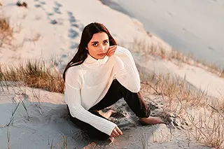 Jeune femme réfléchissant assise sur une dune au crépuscule