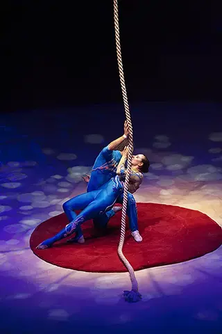 Deux acrobate enlacés autour d'une corde sur une piste de cirque