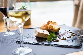 Assiette de foie gras et choux à la crème avec un verre de vin blanc en arrière-plan