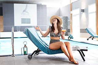 Femme détendue avec un cocktail au bord de la piscine intérieure d'un spa