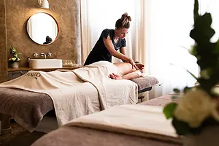 Masseuse professionnelle effectuant un massage des jambes dans un spa d'hôtel