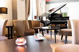 Salon d'hôtel avec piano à queue, tables et chaises pour une ambiance détendue