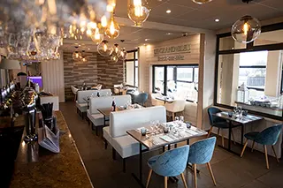 Salle de restaurant contemporaine avec des luminaires élégants et des chaises bleues