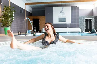 Femme riant et s'amusant dans le jacuzzi d'un spa d'hôtel de luxe