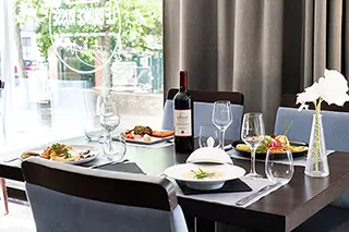 Table de restaurant dressée avec une bouteille de vin et des plats gastronomiques