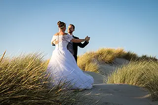 Mariés en train de danser ensemble sur une dune de sable