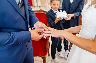 Échange d'alliances entre mariés devant un enfant tenant les anneaux