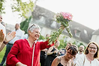 Mariée lançant le bouquet, entourée d'invités souriants