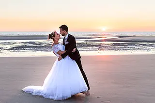 Mariés marchant sur la plage au coucher de soleil